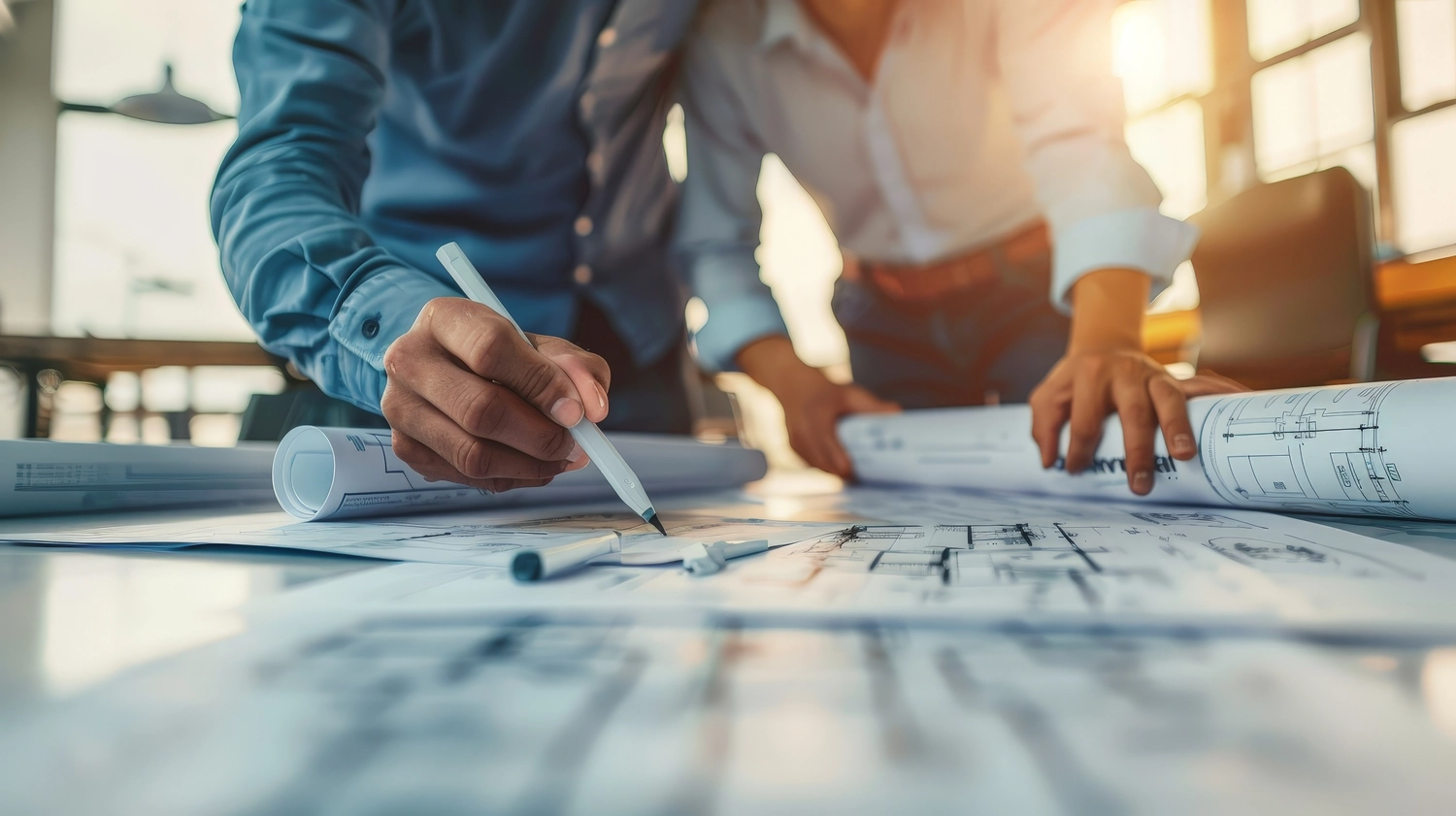 PfG - Planungsbüro für Gebäudetechnik - Ein Ingenieur und ein Architekt prüfen gemeinsam Baupläne und Konstruktionsentwürfe auf einer geschäftigen Baustelle.